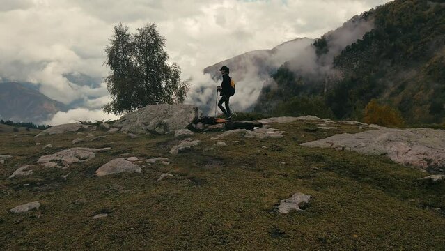 Young woman hiker as she climbs up mountain terrain to summit above clouds