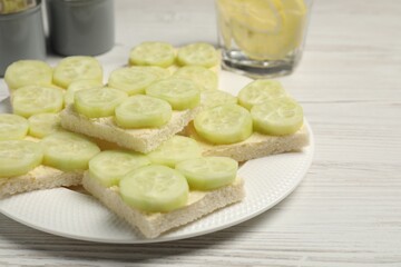 Tasty sandwiches with butter and cucumber served on white wooden table