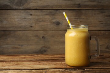 Mason jar with delicious fruit smoothie on wooden table. Space for text