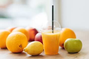 A glass of orange juice on a wooden in a field with fruits