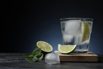 Glass of vodka with lime and ice on black marble table. Space for text