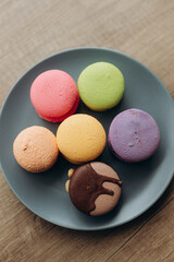 Multi colored macaroons in a plate shot on wooden table
