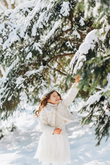 Fototapeta na wymiar A little girl walks in a snowy park.