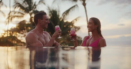 Attractive couple enjoying tropical drinks in the pool at luxury hotel resort In Hawaii - Powered by Adobe