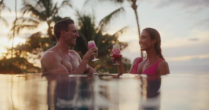 Attractive couple enjoying tropical drinks in the pool at luxury hotel resort In Hawaii