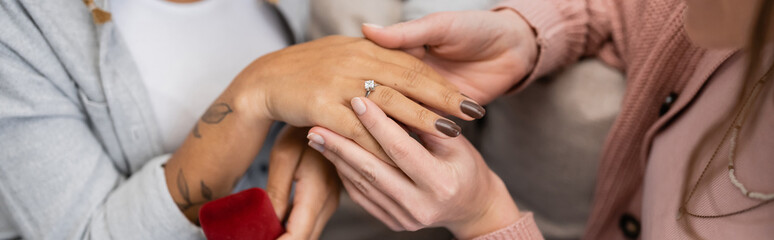 cropped view of lesbian woman wearing engagement ring on finger of african american girlfriend, banner.