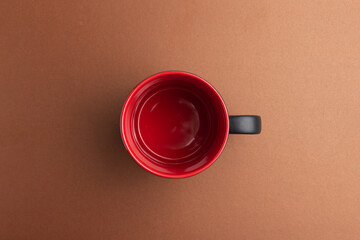 a empty black cup with red inside on a brown background