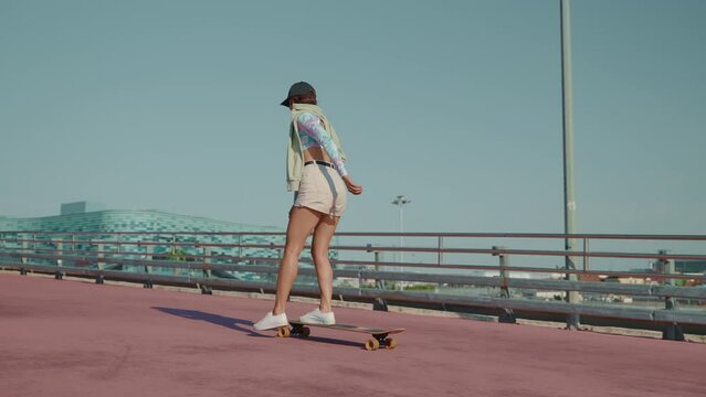 young attractive skater girl riding longboard in urbanistic scape, skateboard ride in summer weekend
