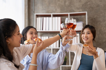 Group of Asian friends gather to celebrate Christmas with champagne and eating pizza at home. Joy of holiday party with friends or colleague concept