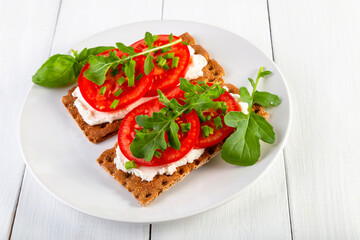 Crispbread with curd cheese, tomatoes, green onions, arugula and basilica. Delicious and healthy breakfast