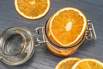 Dry orange slices in glass jar and on table.