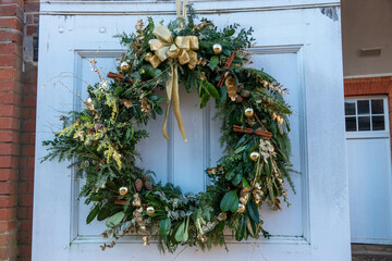 christmas wreath on door with gold ribbon baubles and cinnamon sticks © Penny