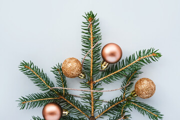Obraz na płótnie Canvas Christmas tree made of natural pine branches and golden balls on a gray background. Flat lay, top view, copy space.