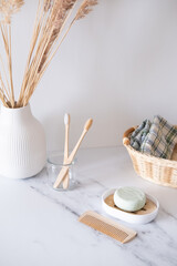Wooden bamboo toothbrushes in a glass, a wooden hair comb and natural soap