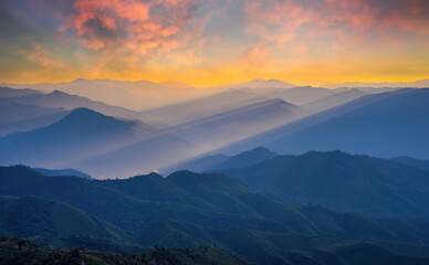 Obraz premium Golden light rays shining down to mountains. Sun rays over valley. Sun rays over hill. Beam of light from clouds on the mountains. oblique rays of sunlight through the mountains. Doi Pui Co, Thailand.