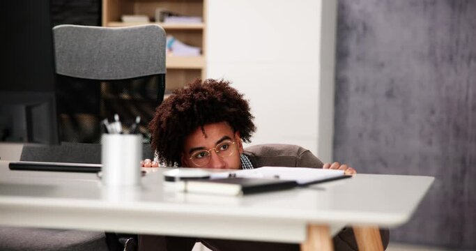 Scared Man Hiding Behind Office Desk