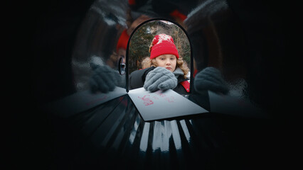 Obraz na płótnie Canvas POV Cute little kid boy puts a letter with his Christmas wishes addressed to Santa Claus, Notrh Pole into the mailbox