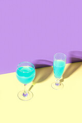 Two glasses of wine. The concept design of the celebration. Minimalistic trendy style. Yellow, Turquoise, Purple color.