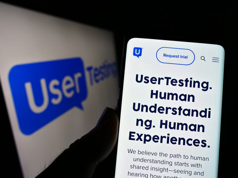 Stuttgart, Germany - 12-02-2022: Person holding cellphone with webpage of US customer experience company UserTesting Inc. on screen with logo. Focus on center of phone display.