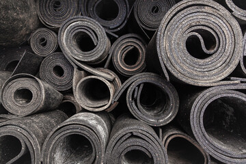 Old sheet rubber of black color, twisted into rolls, top view. rubber waste. - obrazy, fototapety, plakaty