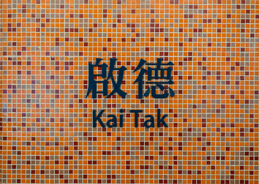Station name sign in Chinese and English with orange colored wall in Tuen Ma Line platform of Kai Tak MTR metro station in KAI TAK, HONG KONG on MAY 2, 2020