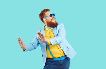 Cool cheerful stylish fat man rejoices and funny dances isolated on light blue background....