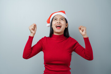 Pretty lovely lady asian thai women in red sweater and santa christmas hat isolated over grey background. dancing