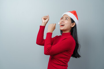 Pretty lovely lady asian thai women in red sweater and santa christmas hat isolated over grey background. dancing