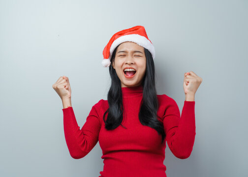 Pretty lovely lady asian thai women in red sweater and santa christmas hat isolated over grey background. wow, surprised, happy, funny