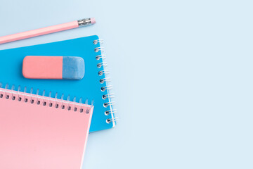 Pink and blue notepad and pencil on a blue background. Place for your text