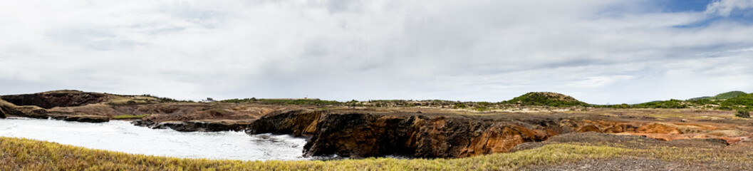 Multicolor sand landscape with ocean and grey sky and clouds