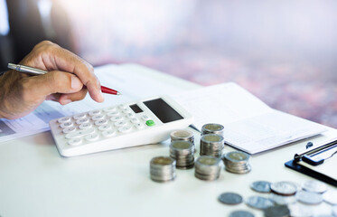 Asian businessman on desk in office using calculator to calculate return on deposit from bank...