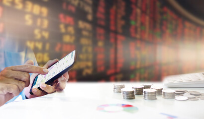 Fototapeta premium Asian businessman making trading online on the smart phone with blur stock market board down at background, Stock exchange market down and inflation concept
