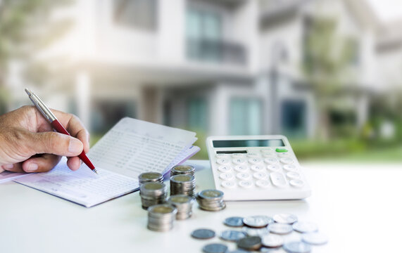 Hand holding pen checking passbook with stack coins and calculator, Concept saving money for house and real estate for family