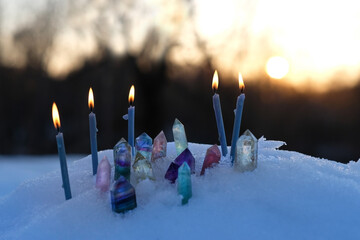 quartz minerals and candles on snow, natural abstract  evening winter background. Gemstones for...