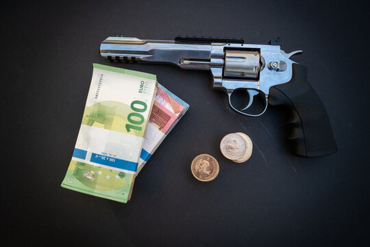 next to a wad of cash and a stack of gold coins lies a revolver