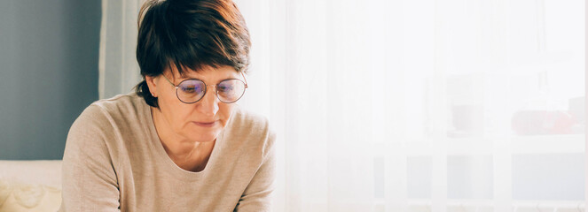 Portrait of middle-aged woman with glasses downcast eyes. Concept psychology emotions mental health