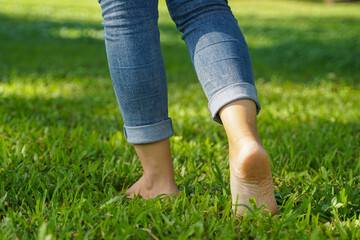 Asian woman walking barefoot on the grass to feel the nature contributes to making people feel at peace have more mental stability. soft and selective focus. 