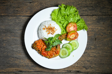 Ayam geprek sambal indonesian food or geprek fried chicken with sambal hot chili sauce served steam rice on white plate