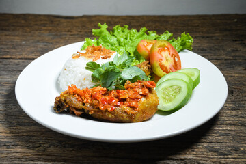 Ayam geprek sambal indonesian food or geprek fried chicken with sambal hot chili sauce served steam rice on white plate