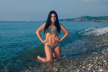 A young brunette woman on a beach of pebbles. Young woman on the seashore at a seaside resort