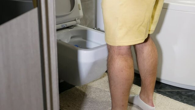 Young man with a problem of the genitourinary system. A man runs in the toilet, prostate adenoma, a man urinates in the toilet. Problems of the male genitourinary system in a man.