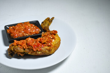 Ayam geprek sambal indonesian food or geprek fried chicken with sambal hot chili sauce. Selective Focus