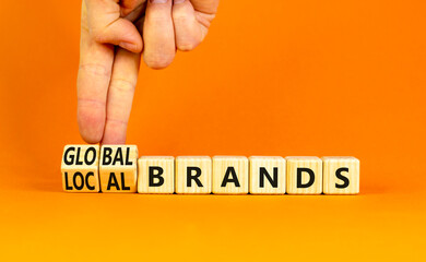 Global or local brands symbol. Concept words Global brands and Local brands on wooden cubes. Businessman hand. Beautiful orange background. Business global or local brand concept. Copy space.