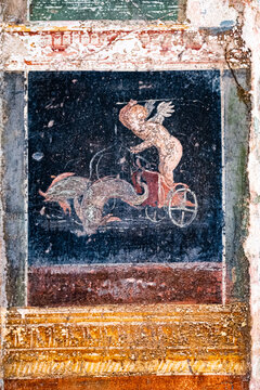 Winged Amorino leads a fish-drawn chariot, a figure of divinity of ancient Rome in Pompeii. Pompeii was destroyed by the volcanic eruption of Vesuvius in 79 BC