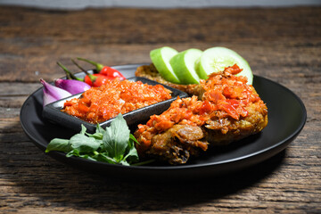 Ayam geprek sambal indonesian food or geprek fried chicken with sambal hot chili sauce on black plate