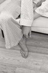 woman in pajamas sits in chair . close-up female hand and leg