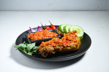 Ayam geprek sambal indonesian food or geprek fried chicken with sambal hot chili sauce served steam rice. Ayam Geprek is a typical Indonesian flour fried chicken dish that is pulverized or crushed
