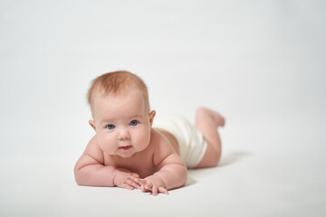 baby lying on his belly looking at the camera with interest against a white background