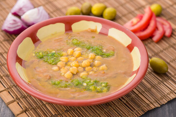 Fol with chickpea, tomato, and olives served in dish isolated on table side view of arabic food